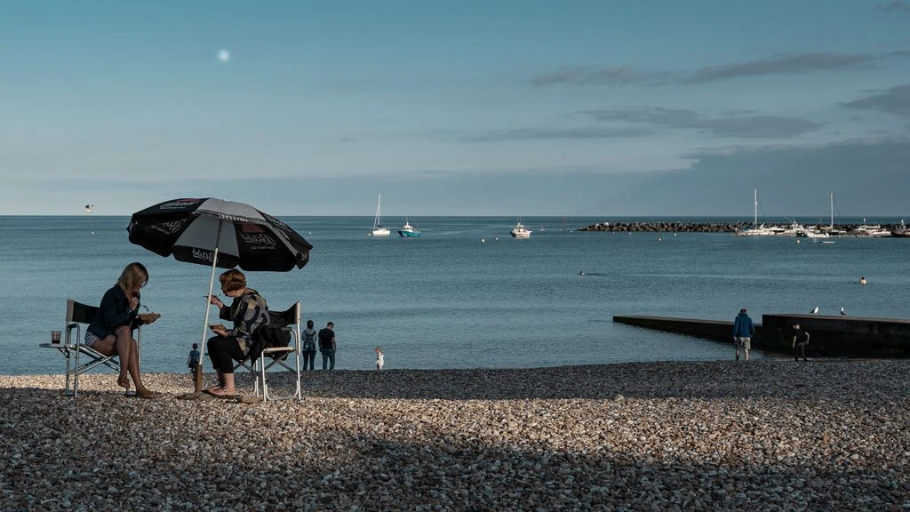 Lyme Regis harbour at golden hour with the Jurassic cliffs in the distance
